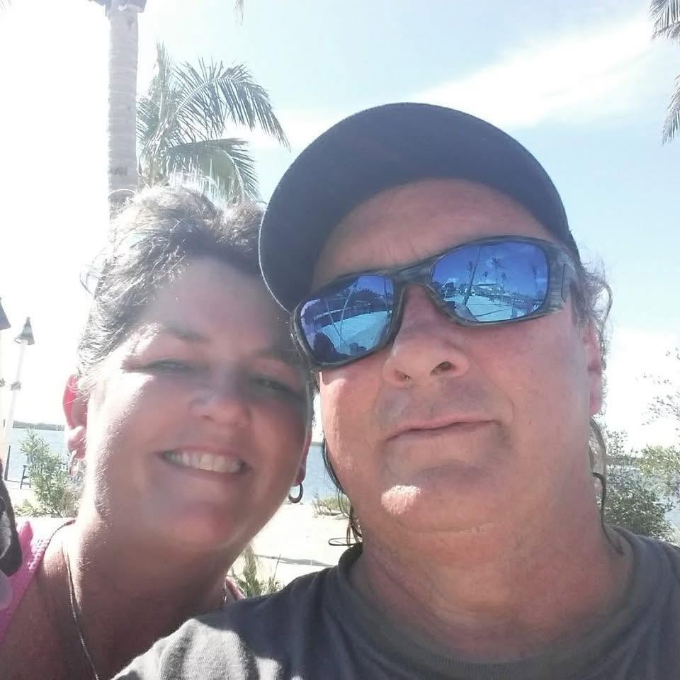 Mark Skowron and his wife Eileen smiling under Florida palms
